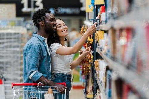 Preview: selective focus of happy african american man standing with asian woman pointing with finger at