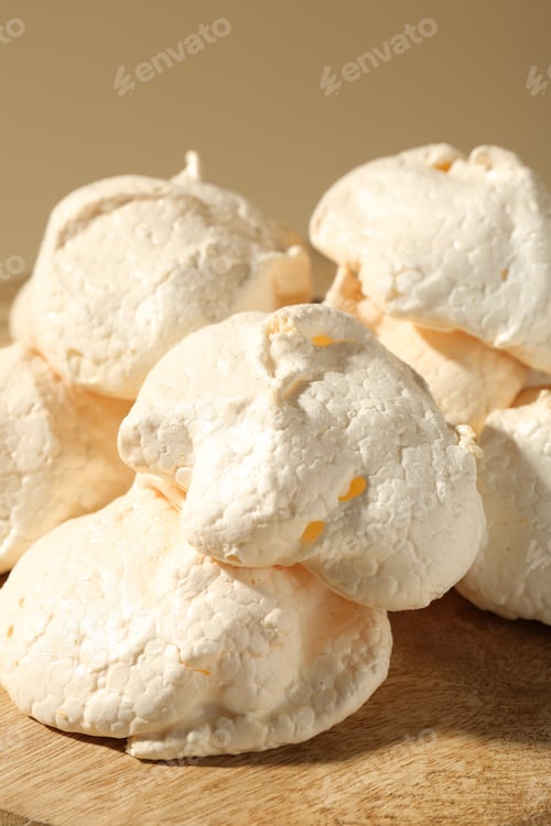 Preview: Delicious homemade meringue cookies on wooden table against beige background, closeup