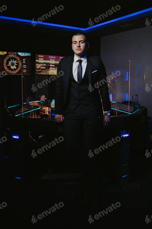 Preview: Young man in an elegant black suit with a tie posing in the casin