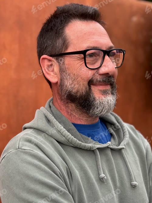 Preview: Portrait of adult man smiling and looking in front wearing glasses and green sweater