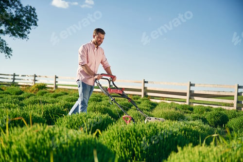 Preview: Red colored lawn mower. Adult farmer is outdoors
