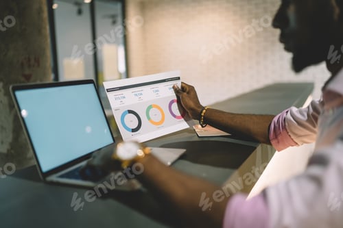 Preview: African American employee copying information from paper to computer in office