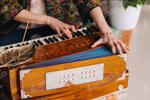 Preview: Hands of a woman sitting on the floor and playing the harmonium during the practice of kundalini
