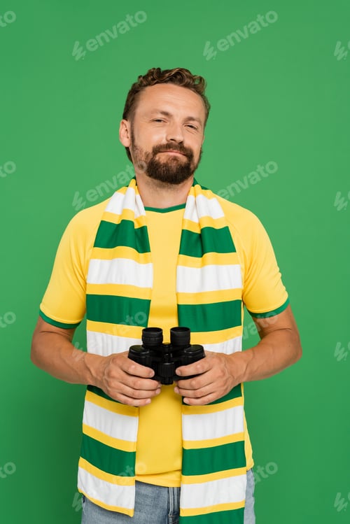 Preview: bearded man in striped scarf holding binoculars during football match isolated on green