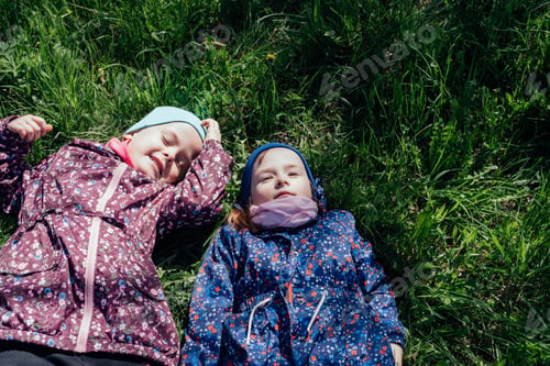 Preview: Two cute little girls lie on the fresh spring grass