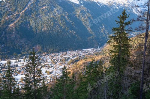 Preview: Alpen village nestled in forest valley bathed in golden hour light with snow capped peaks distant