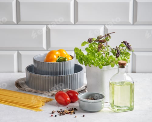 Preview: Raw spaghetti with tomatoes, basil, pepper and olive oil on a white brick background.