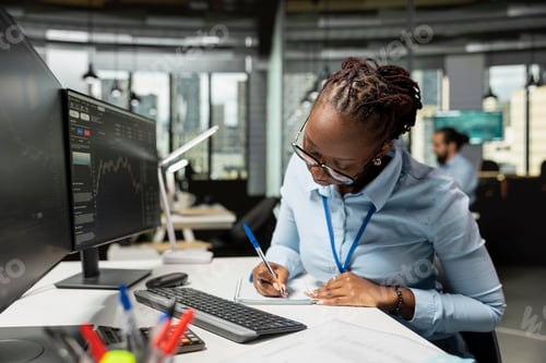Preview: Trader in prop firm office taking notes while analyzing candlestick charts