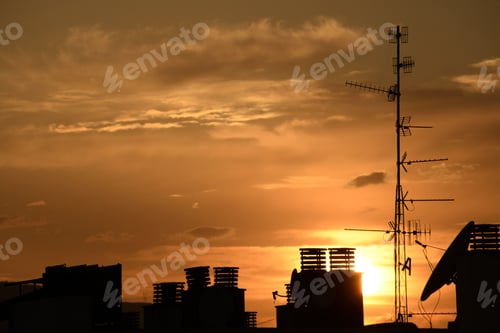 Preview: Silhouettes of antenna and chimneys during the orange sunset