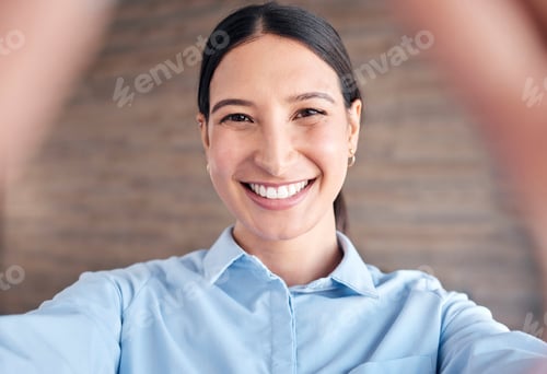 Preview: Closeup portrait of a cheerful mixed race young woman standing in an office taking a selfie