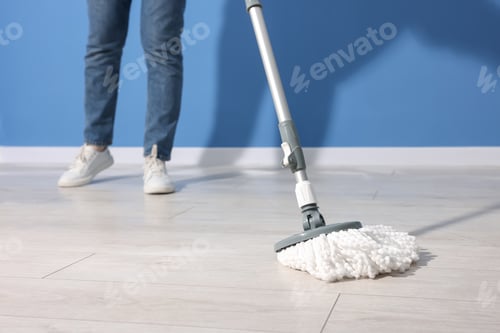 Preview: Woman cleaning floor with string mop indoors, closeup