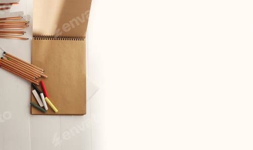 Preview: Empty copy space kraft paper note album and color pencils, pastel chalk. Flat lay, top view.