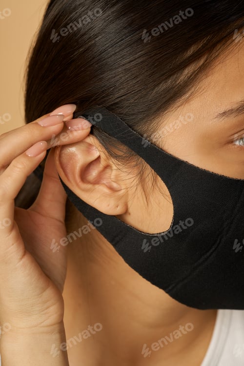 Preview: Close up shot of young woman putting on black facial mask
