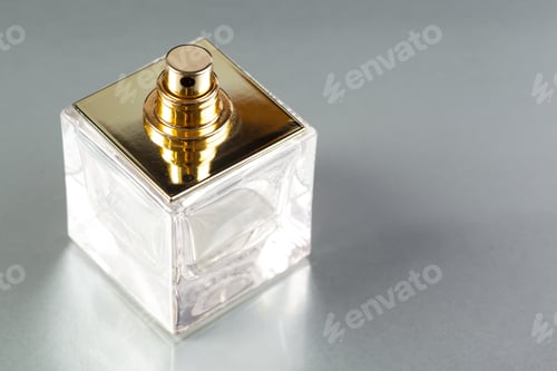 Preview: Clear glass perfume bottle on a smooth surface with a golden cap and simple design