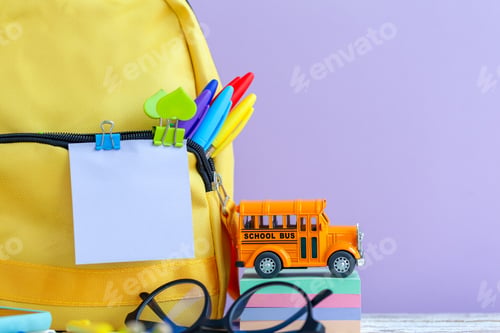 Preview: Full yellow school backpack with stationery on table on purple background.