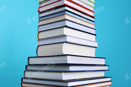 Preview: Stack of hardcover books on light blue background, closeup