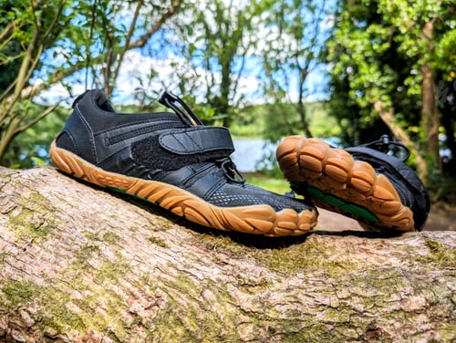 Preview: Closeup of black barefoot shoes on tree branch in forest, fashion and lifestyle concept, nature bac