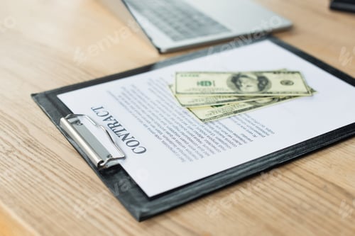 Preview: dollar banknotes on contract near blurred laptop, anti-corruption concept