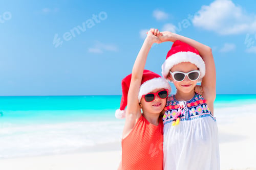 Preview: Adorable little kids in Santa hat during Christmas beach vacation. New Year on the beach