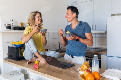 Preview: young attractive couple of man and woman cooking breakfast together in morning at kitchen