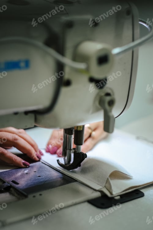 Preview: Vertical shot of female hands using a sewing machine