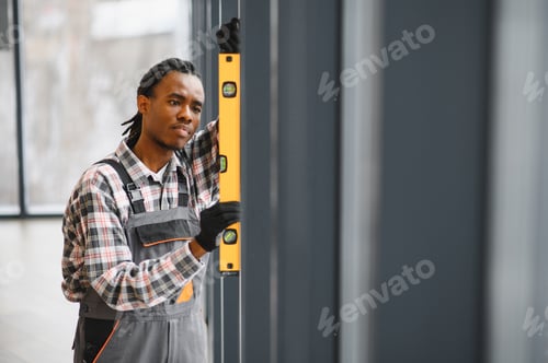 Preview: African American Skilled technician using level for precise installation