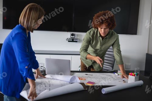 Preview: Diverse male and female colleagues in office discussing over blueprint document