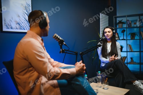 Preview: Female podcaster in headphones interviewing man guest using microphone, smiling