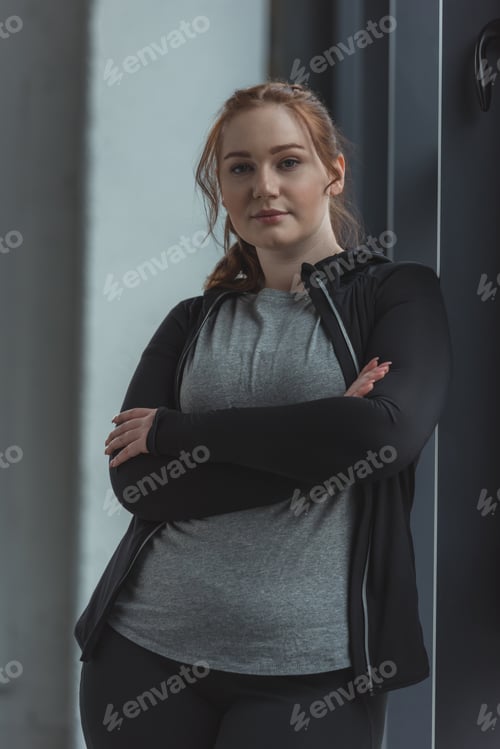 Preview: Overweight girl standing by window in gym