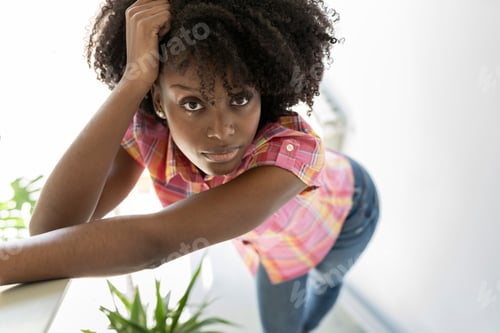 Preview: From above of African American female with afro hairstyle wearing cotton shirt and jeans touching