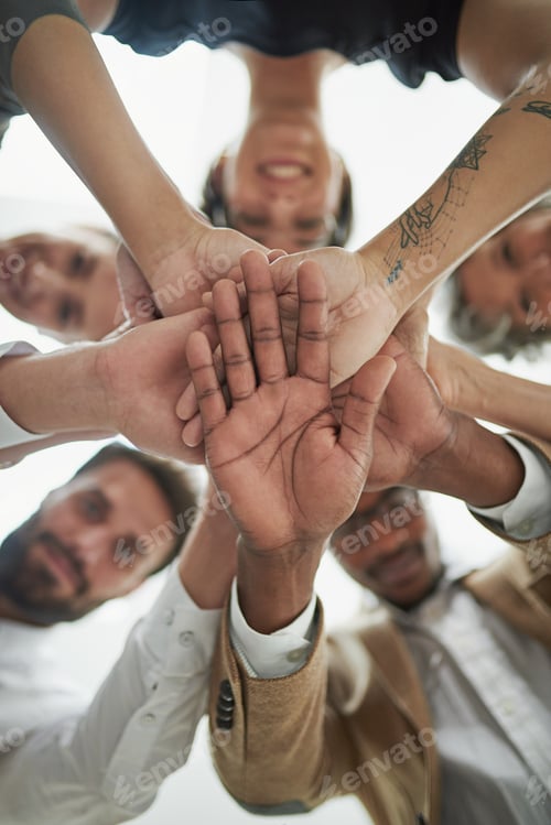 Preview: Low angle portrait of a group of businesspeople putting their hands in a pile