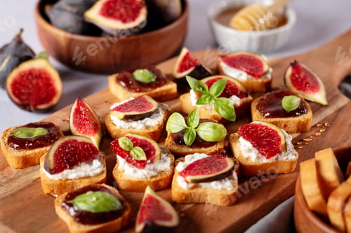 Preview: Toasts with figs, ricotta and fig marmalade sprinkled with honey on wooden board