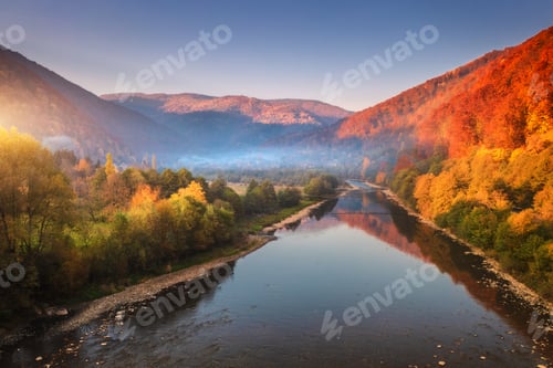 Preview: Aerial view of blue lake in mountains with red and orange forest