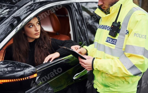 Preview: Male police officer in green uniform checking vehicle on the road