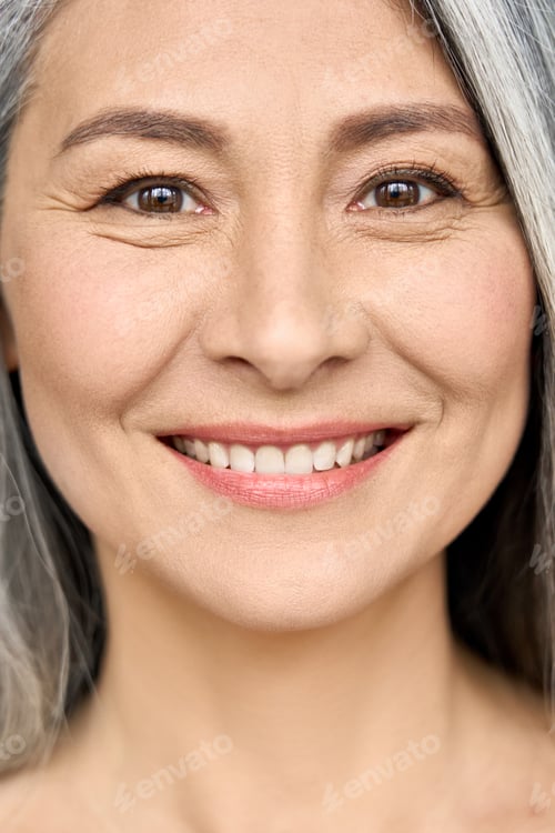 Preview: Closeup portrait of Asian smiling mature woman with perfect natural makeup.