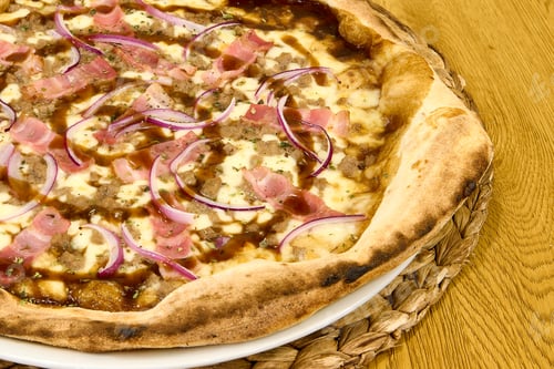 Preview: Pizza with ham and onion on a plate on a wooden table