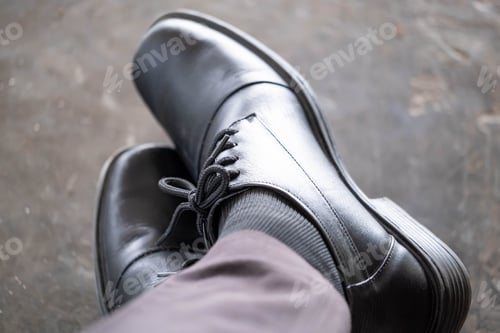 Preview: Close-up of black formal shoes and gray socks with legs crossed