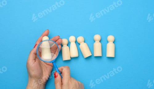 Preview: Wooden figures of men on a blue background and a red magnifying glass
