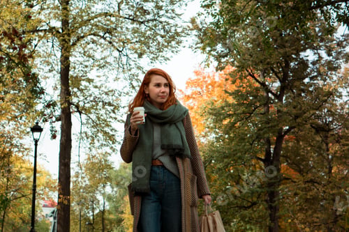 Preview: Beautiful woman walking in park in autumn