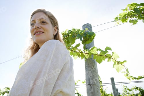 Preview: Mid adult woman in vineyard with vines