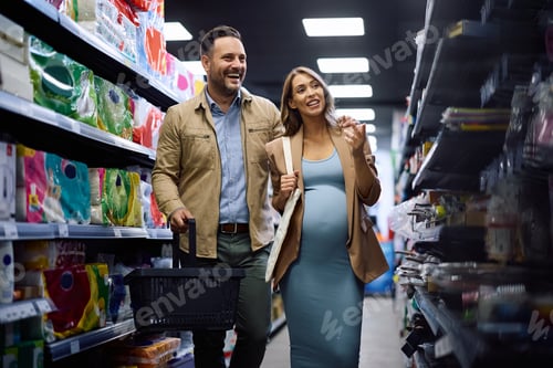 Preview: Happy pregnant couple talking while buying at supermarket.