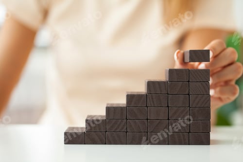 Preview: Close up Woman hand arranging wood block stacking as step stair.
