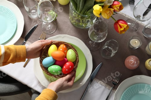 Preview: Woman setting table for festive Easter dinner at home, top view