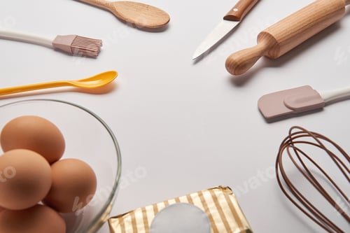 Preview: cooking utensils, butter and eggs in bowl on grey surface