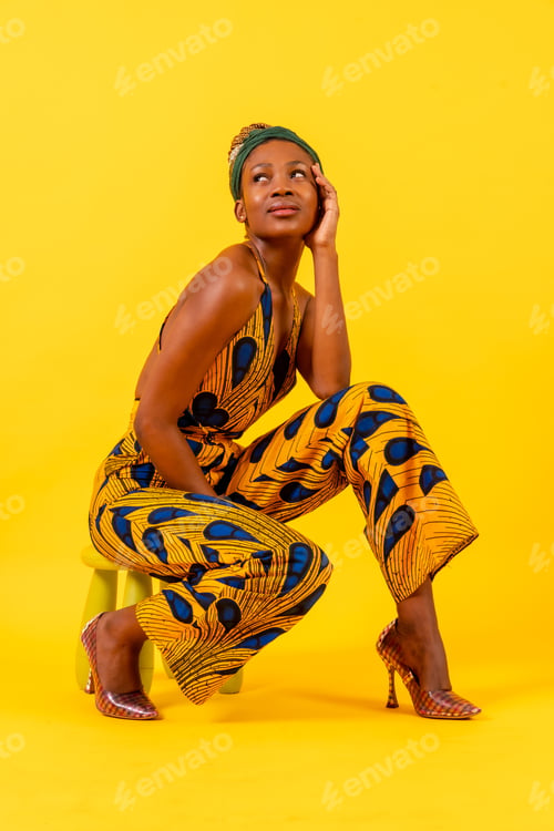 Preview: African young woman in traditional dress on yellow background, seductive look
