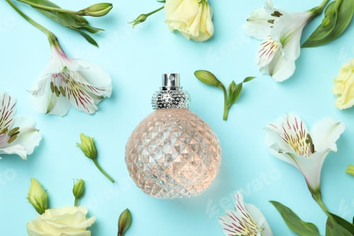 Vista previa: Bottle of perfume and flowers on blue background