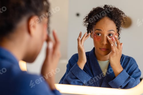 Preview: Biracial woman in bathrobe wearing eye mask in bathroom