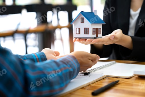 Preview: real estate agent salesman holds a model of a house and sends it to customers as an example, a sampl