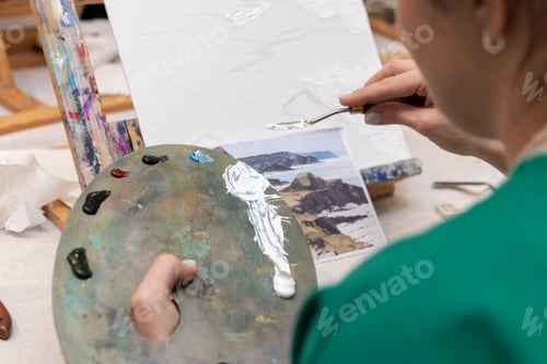 Preview: student uses white paint smeared on a palette to draw on canvas with a palette knife