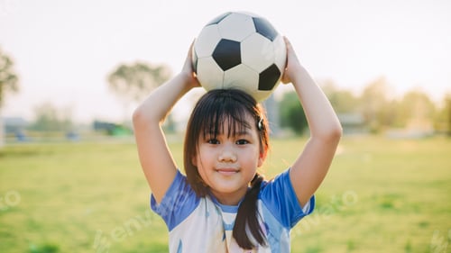 Preview: Little girl playing soccer football at green grass field for exercise